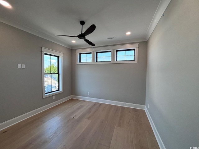 empty room with crown molding, visible vents, ceiling fan, wood finished floors, and baseboards