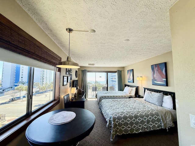 bedroom featuring access to outside, a textured ceiling, and carpet