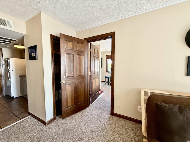 corridor with carpet floors, visible vents, and a textured ceiling