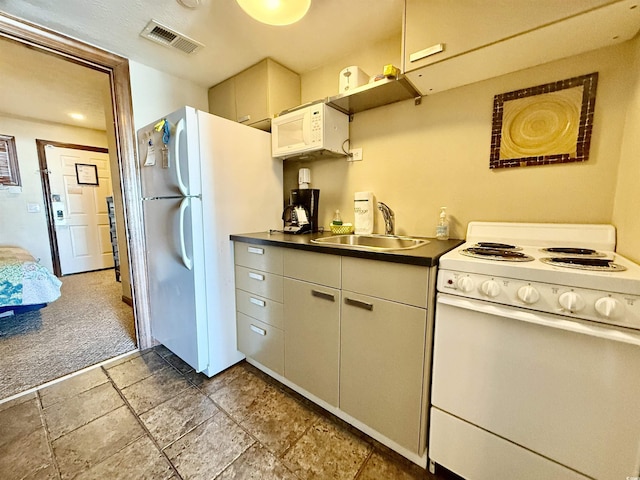 kitchen featuring white appliances, visible vents, dark countertops, carpet flooring, and a sink