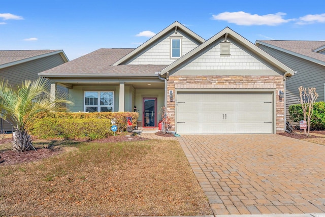 craftsman-style house with decorative driveway, roof with shingles, and an attached garage