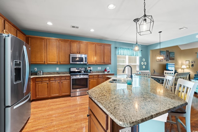 kitchen featuring appliances with stainless steel finishes, brown cabinets, visible vents, and a sink