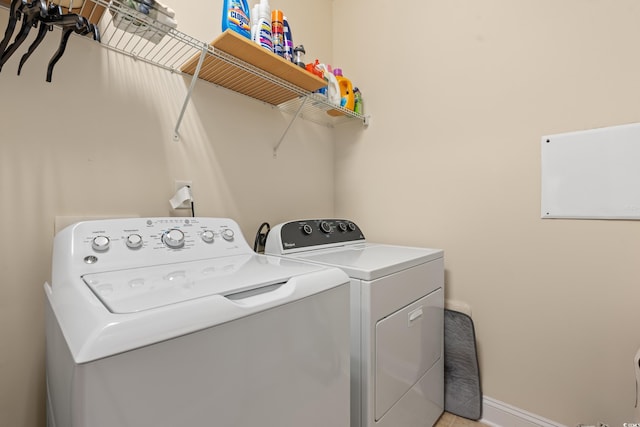 washroom with laundry area, baseboards, and washing machine and clothes dryer