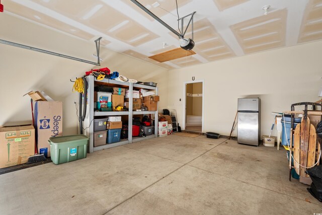 garage with a garage door opener and freestanding refrigerator