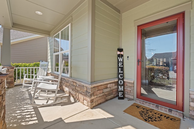 doorway to property featuring a porch and brick siding