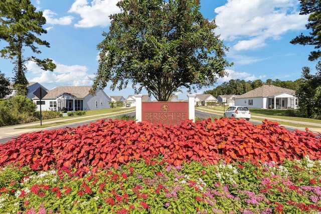 community / neighborhood sign featuring a residential view and a lawn