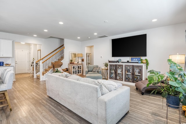 living area featuring light wood finished floors, stairway, and recessed lighting