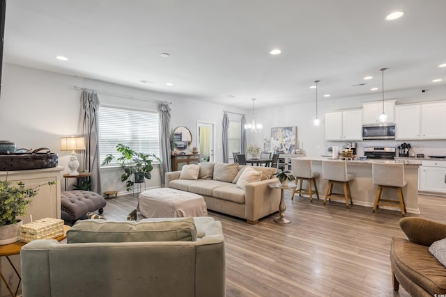 living room featuring an inviting chandelier, light wood-style flooring, and recessed lighting