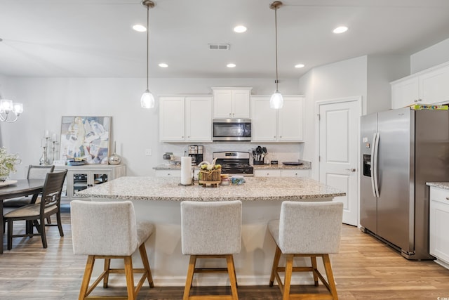 kitchen with light wood-style flooring, stainless steel appliances, a center island, visible vents, and decorative backsplash