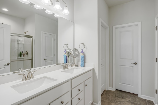 bathroom with double vanity, a shower stall, and a sink