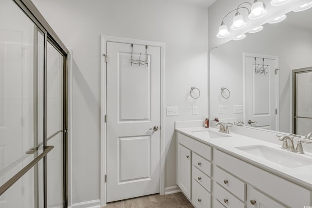 bathroom with double vanity, a shower with door, and a sink