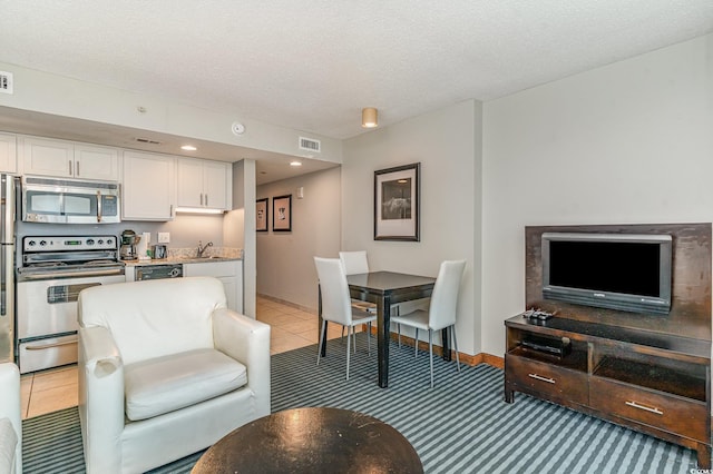 living room with light tile patterned floors, baseboards, visible vents, and a textured ceiling