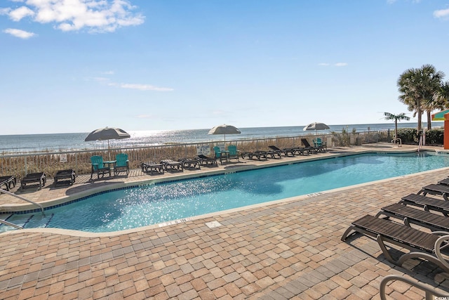 pool featuring a water view, a patio, and fence