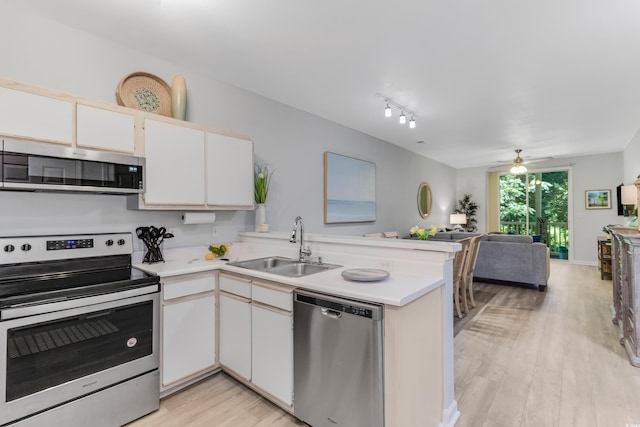 kitchen featuring a peninsula, a sink, stainless steel appliances, light countertops, and open floor plan