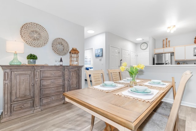 dining area with baseboards and light wood finished floors