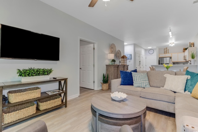 living area with light wood-style floors, baseboards, and ceiling fan