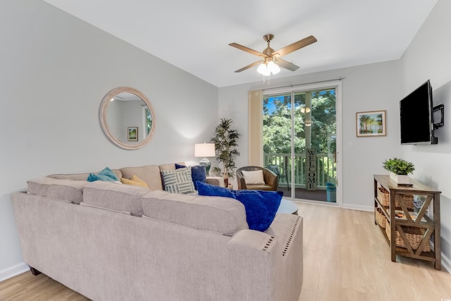 living area featuring baseboards, light wood-type flooring, and a ceiling fan