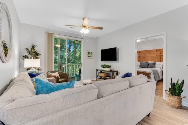 living room featuring a ceiling fan, visible vents, and light wood finished floors