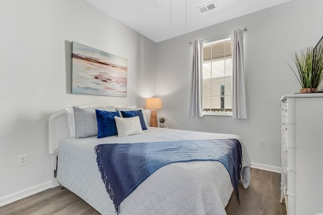 bedroom featuring visible vents, baseboards, and wood finished floors