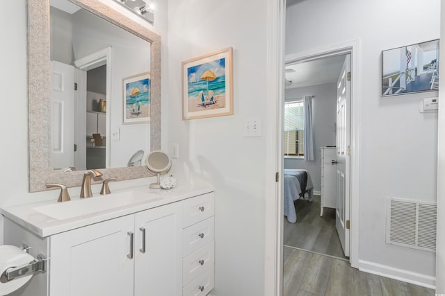 bathroom featuring visible vents, wood finished floors, connected bathroom, baseboards, and vanity