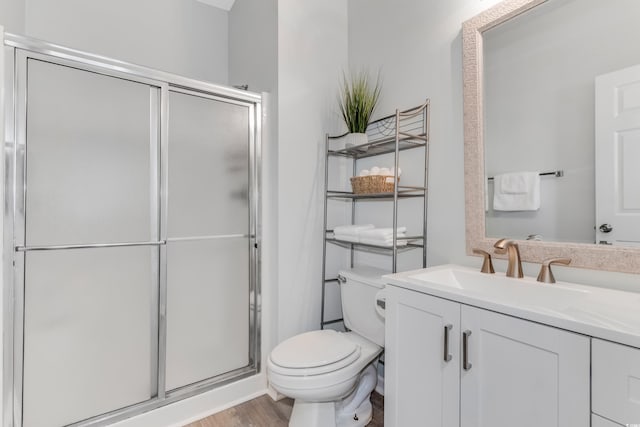 bathroom with vanity, a shower stall, toilet, and wood finished floors