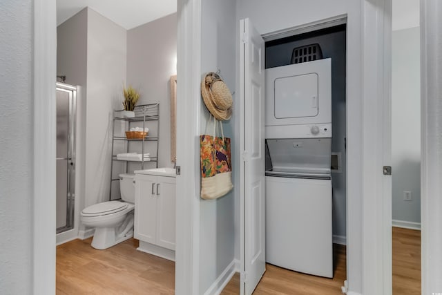 washroom with stacked washer / dryer, light wood-style flooring, and laundry area