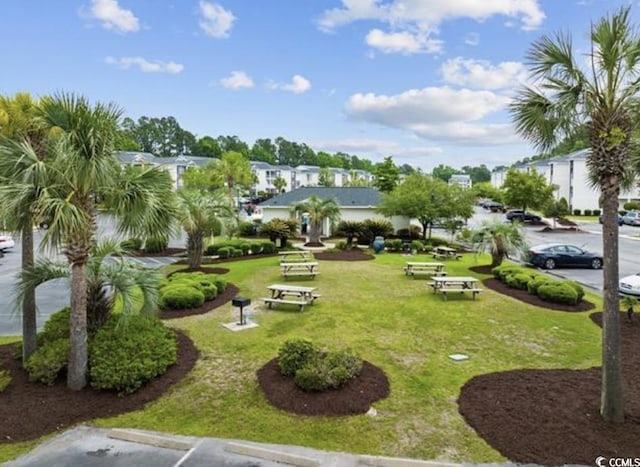 view of home's community featuring a lawn and uncovered parking