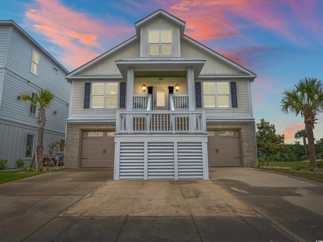 beach home with a garage, concrete driveway, brick siding, and board and batten siding