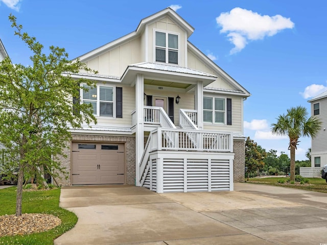 coastal inspired home with brick siding, covered porch, board and batten siding, a garage, and driveway