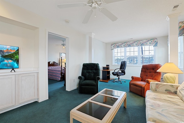 living area featuring dark colored carpet, visible vents, baseboards, and ceiling fan