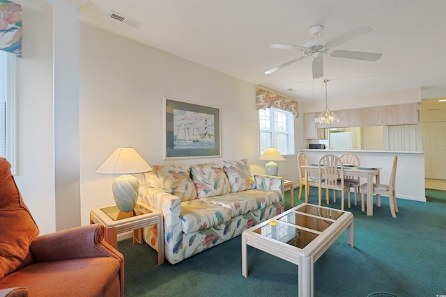 carpeted living area with visible vents and ceiling fan with notable chandelier