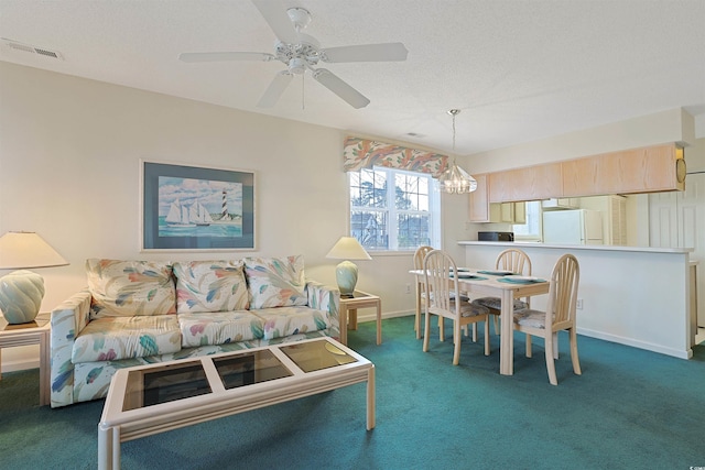 carpeted dining area with visible vents, ceiling fan with notable chandelier, baseboards, and a textured ceiling