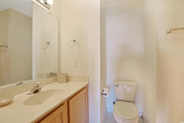 bathroom with toilet, vanity, and baseboards