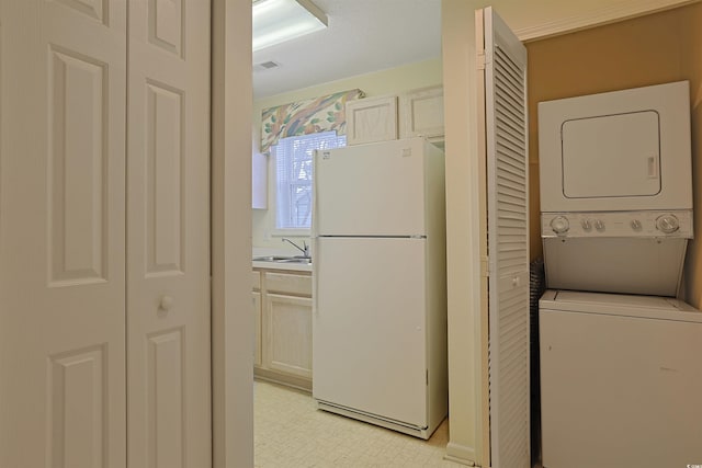 washroom with light floors, visible vents, laundry area, a sink, and stacked washer and clothes dryer