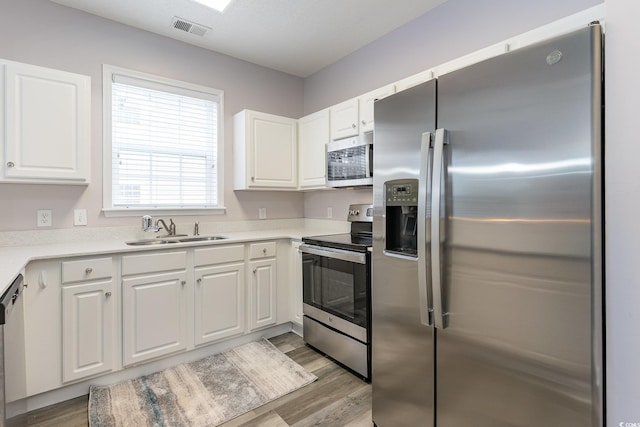 5801 Oyster Catcher Dr Unit 724, North Myrtle Beach, SC 29582 - kitchen featuring appliances with stainless steel finishes, a sink, light wood-type flooring, white cabinetry, and light countertops