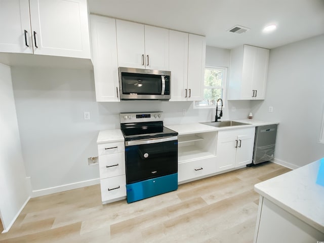kitchen with light wood-style flooring, baseboards, a sink, and appliances with stainless steel finishes