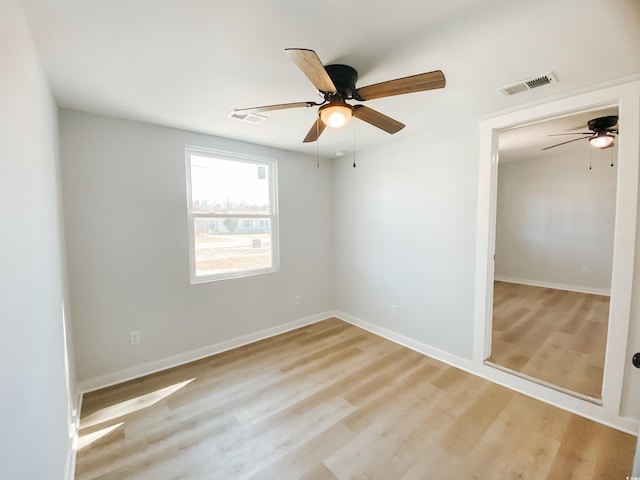 empty room featuring light wood-type flooring, baseboards, a ceiling fan, and visible vents