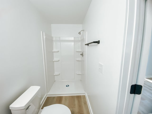 bathroom with toilet, walk in shower, wood finished floors, and baseboards