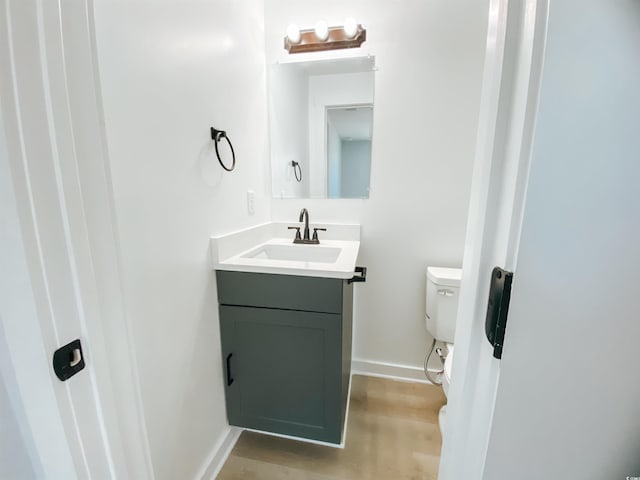 bathroom with baseboards, vanity, and toilet