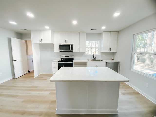 kitchen with a sink, light wood-style floors, baseboards, appliances with stainless steel finishes, and visible vents