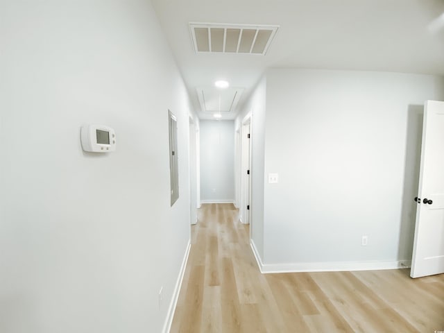 hallway with attic access, electric panel, light wood-type flooring, baseboards, and visible vents