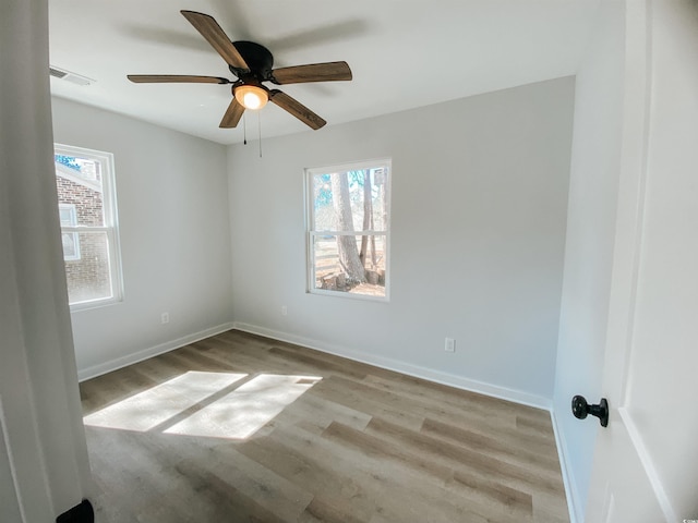 spare room featuring wood finished floors, visible vents, baseboards, and ceiling fan