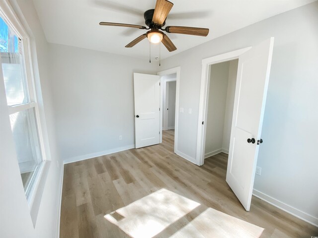 unfurnished bedroom with baseboards, a ceiling fan, and light wood-style floors