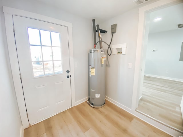 doorway to outside with light wood finished floors, electric water heater, baseboards, and visible vents