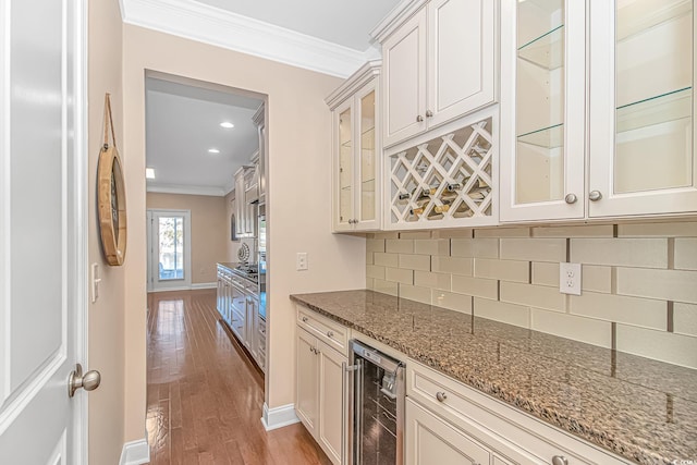 bar with beverage cooler, backsplash, wood finished floors, and crown molding