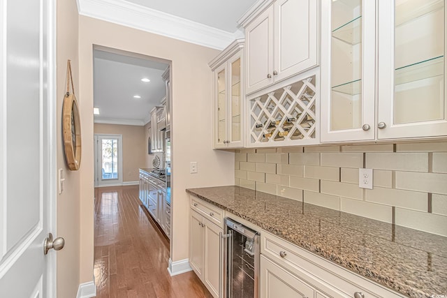 bar area featuring wine cooler, crown molding, backsplash, wood finished floors, and baseboards