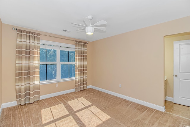 spare room with a ceiling fan, visible vents, and baseboards