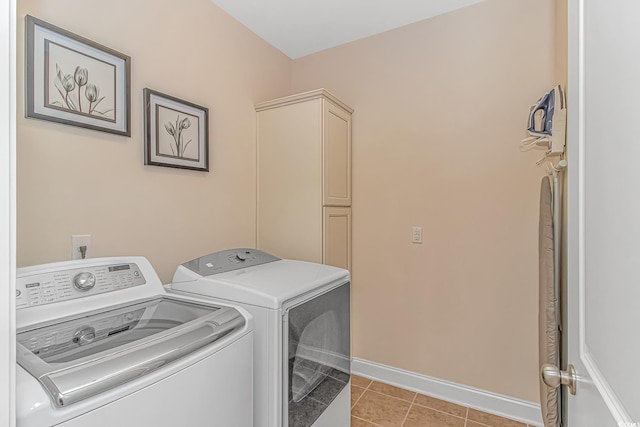 laundry room with washing machine and clothes dryer, cabinet space, light tile patterned flooring, and baseboards