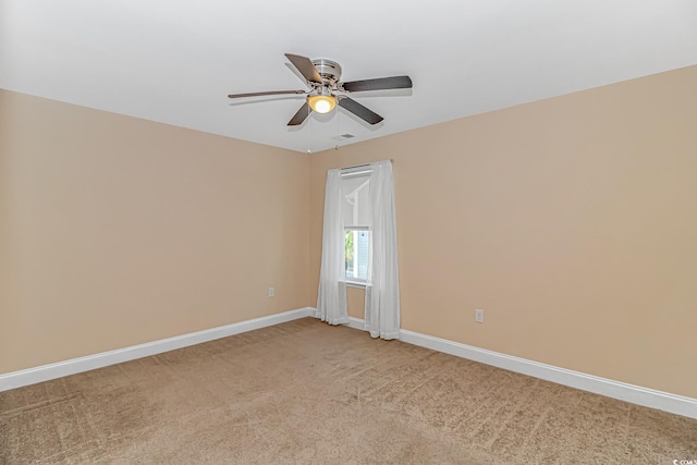 spare room featuring light carpet, ceiling fan, and baseboards