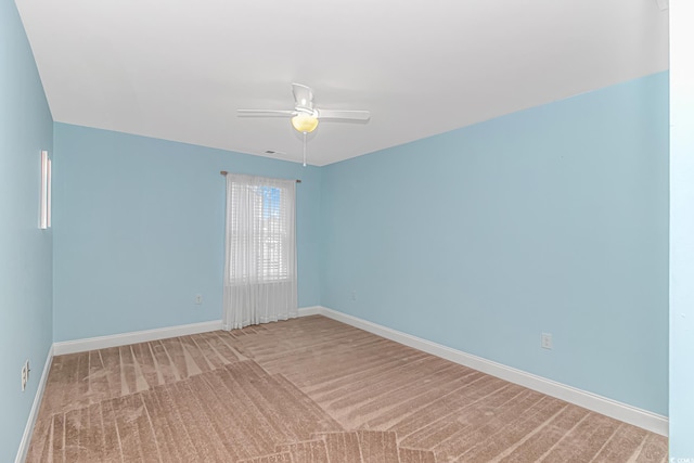 carpeted spare room with a ceiling fan and baseboards